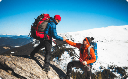 two people helping each other climb a rock