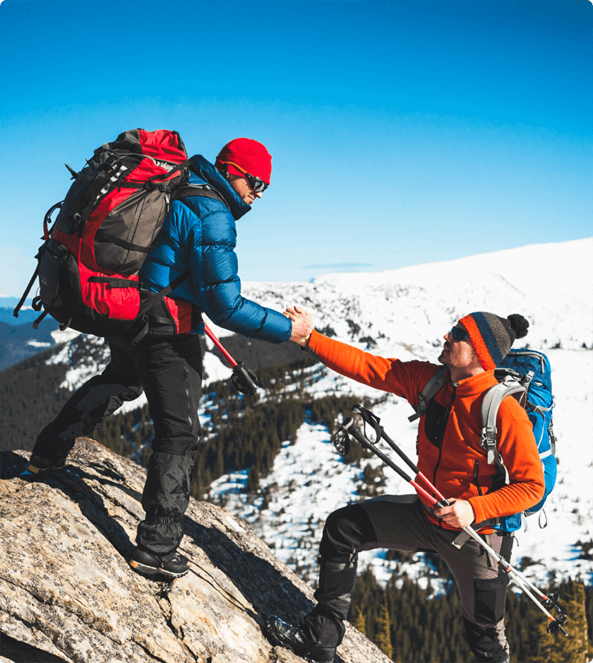 two people helping each other climb a rock