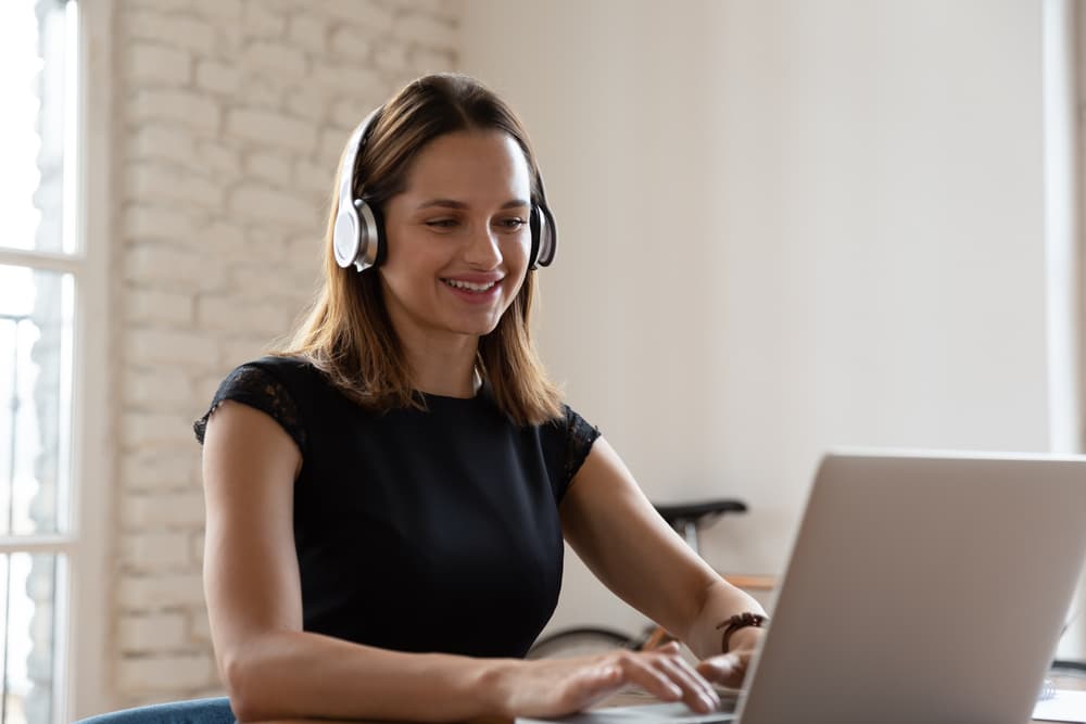 virtual assistant wearing headphones and working on a laptop