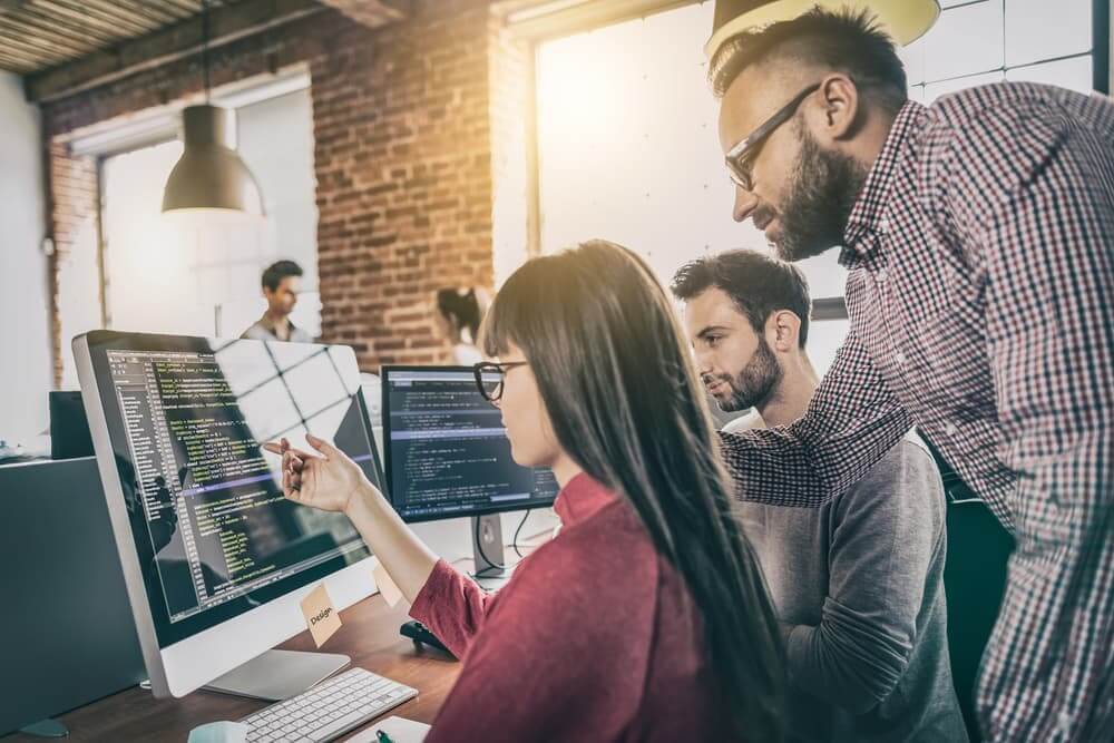 Team collaborating on a computer screen in a modern office.