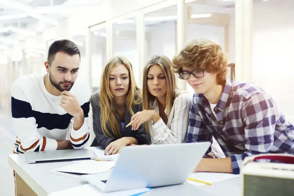 4 individuals looking at a laptop screen