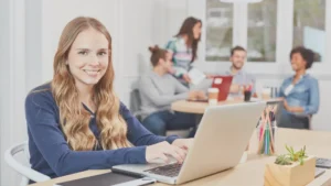 a blog writer smiling working on an outsourced content writing project that was assigned to them and a team of writers in the background