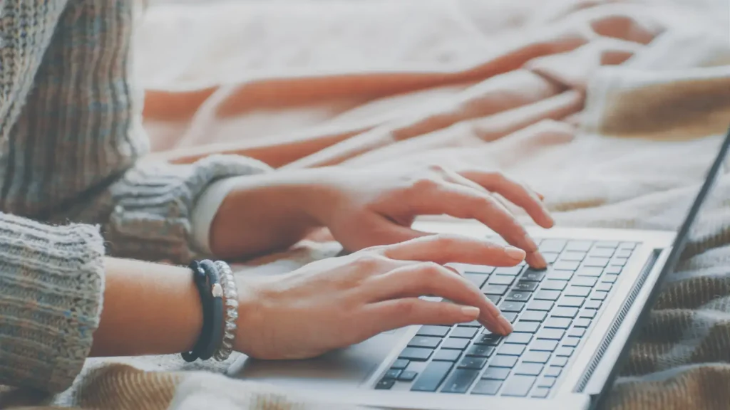 writer's hands typing while working on an outsourced blog article