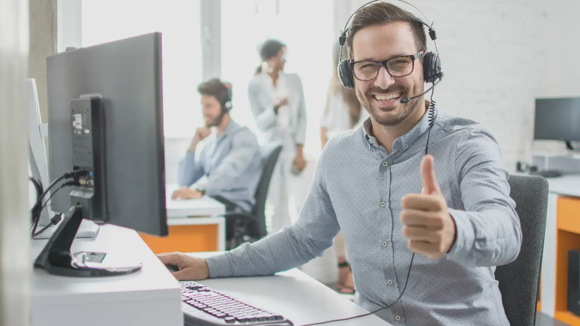 customer service specialist smiling with a thumbs up while working