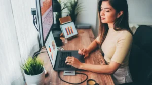 a busy business owner working from 3 different screens sitting at a desk