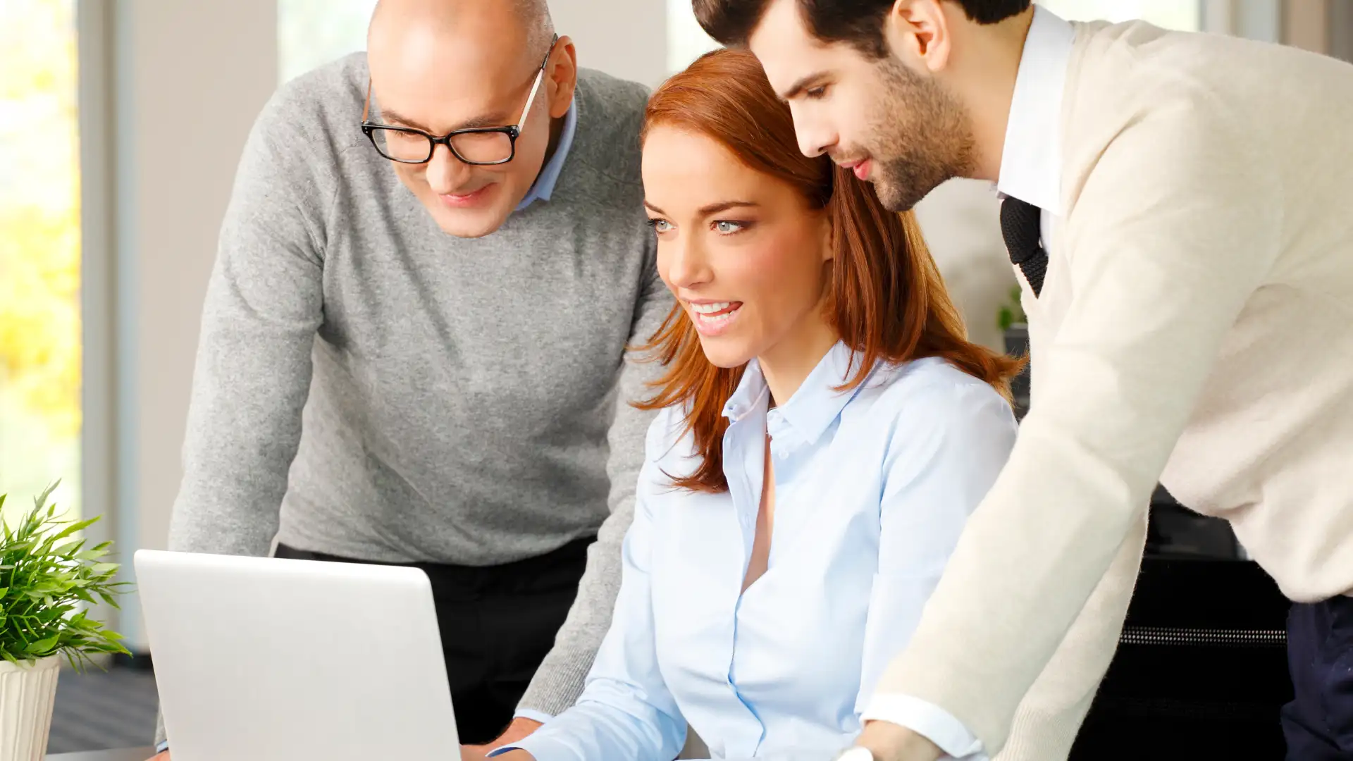 Team collaborating around a laptop, discussing eCommerce solutions.