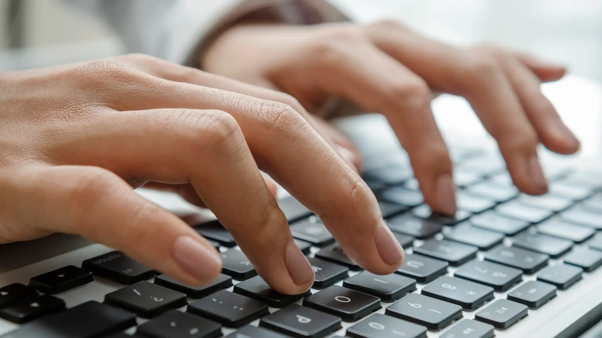 Close-up of hands typing on a keyboard, symbolizing efficient Shopify product data entry
