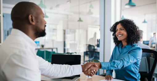 Two professionals shaking hands in an office setting.