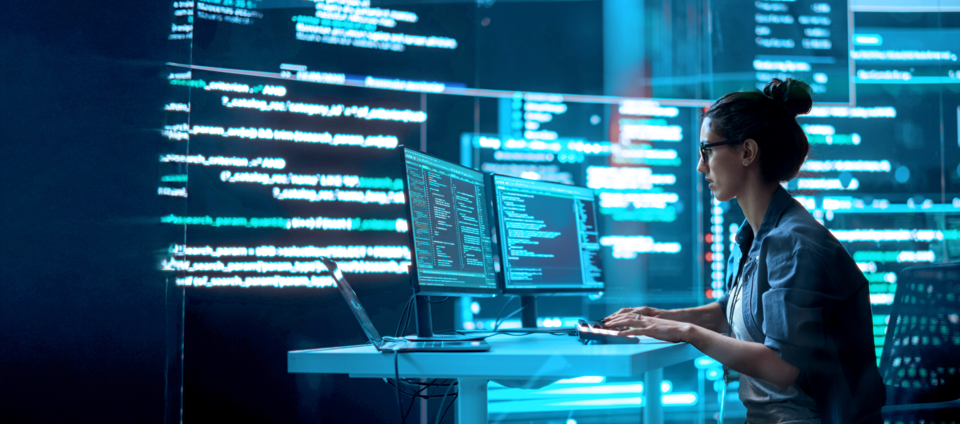 IT professional working on multiple monitors with code displayed on screens.