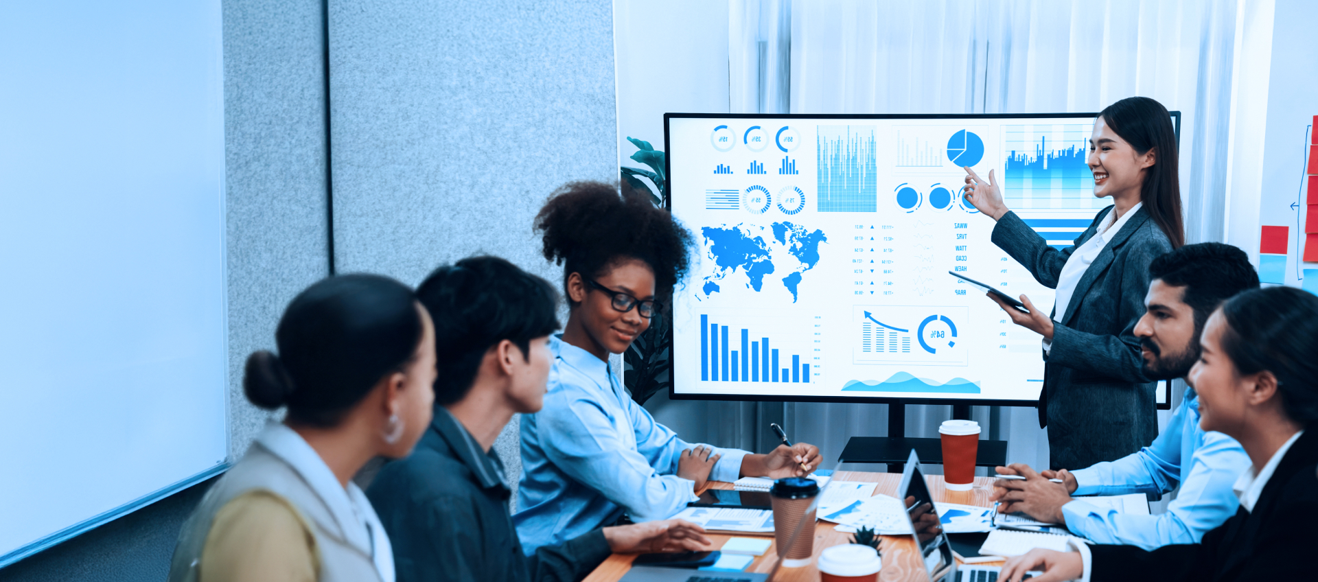 Team in a meeting discussing data charts on a presentation screen.