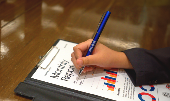 A person writing on a monthly report document