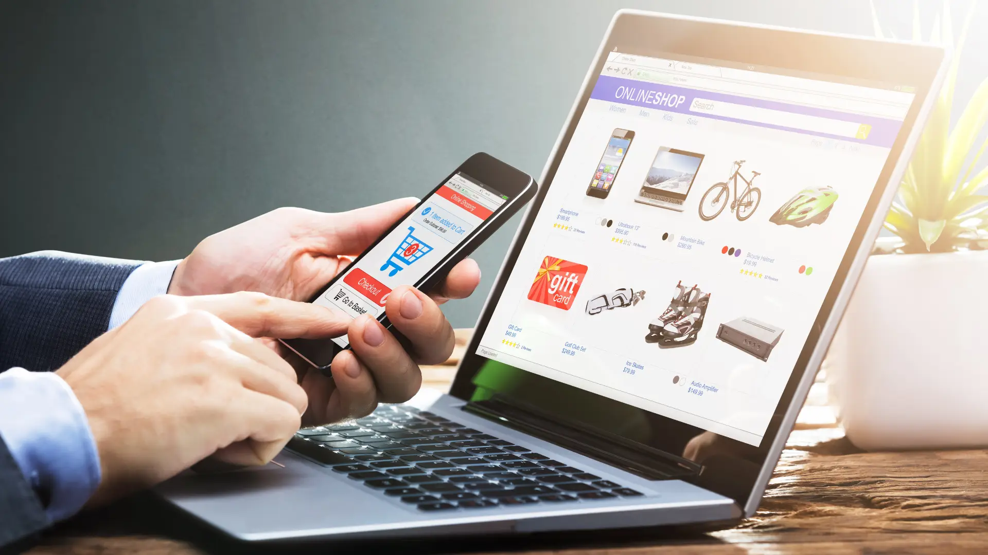 Person using a smartphone and laptop to shop online, highlighting the importance of eCommerce optimization during peak seasons.