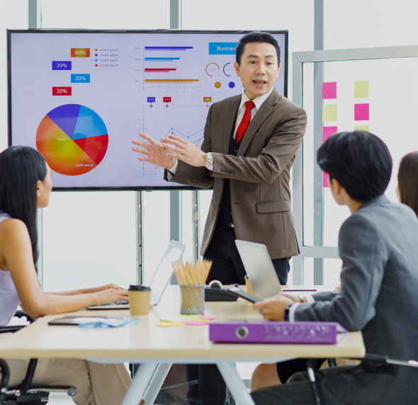 A professional giving a presentation to a team in a modern office, with charts and graphs displayed on a large screen