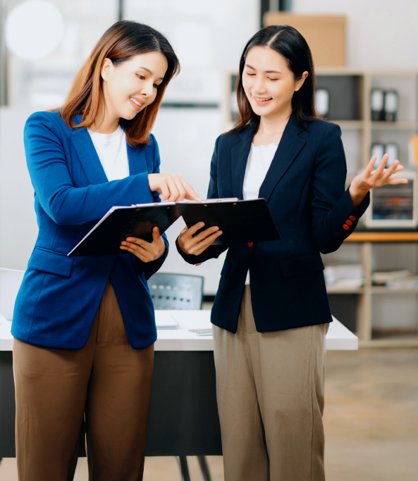 Two professionals discussing documents in an office setting.