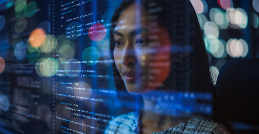 Woman looking at computer code with reflections of data and lights