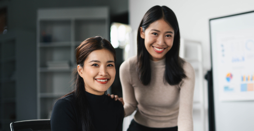 Two colleagues smiling in a modern office setting.