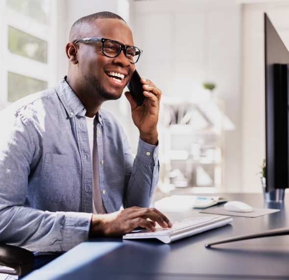 Smiling professional talking on the phone while working at a computer.