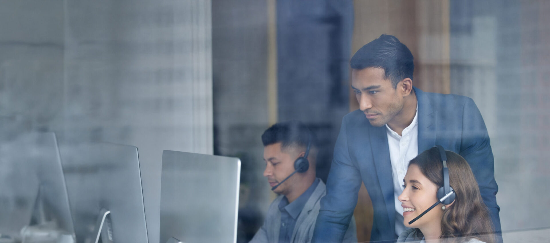 Team of customer support representatives wearing headsets working at computers.