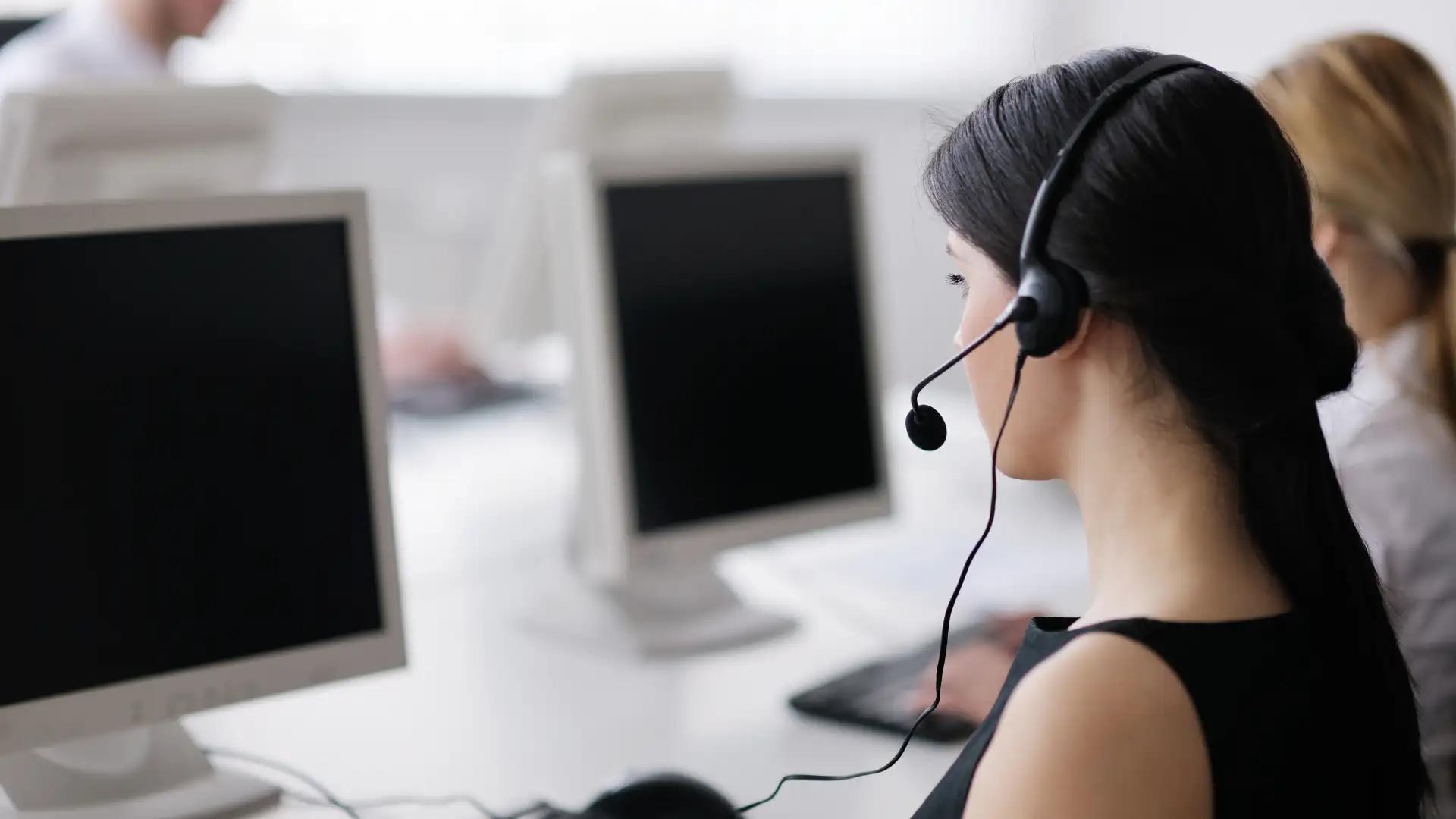 Customer service agent wearing a headset in front of computer monitors