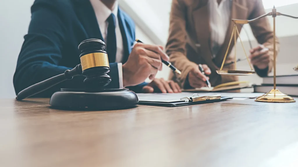 Lawyers reviewing documents at a desk with a gavel and legal scale.