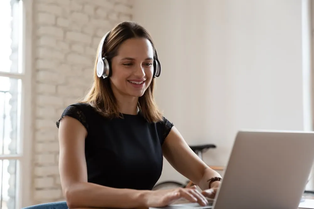 virtual assistant wearing headphones and working on a laptop
